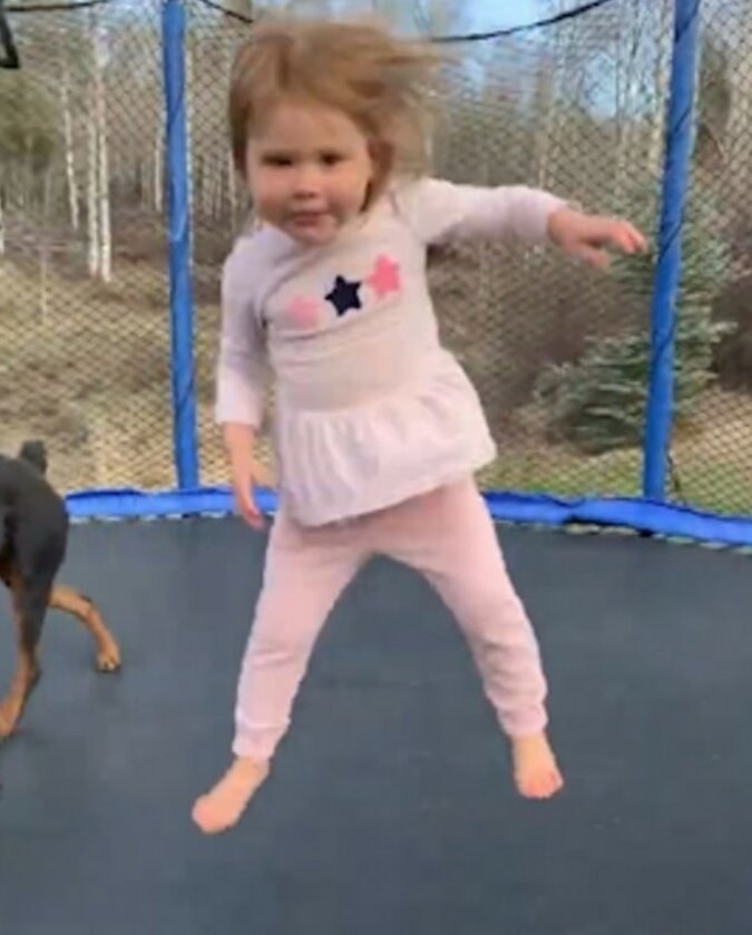 &quot;Ungezügelter Spaß&quot; Ein kleines Mädchen und sein Hund springen freudig